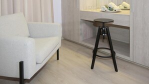 Ein modernes Zimmer mit einer Couch, einem Hocker, einem Spiegel und einem Holzschrank.