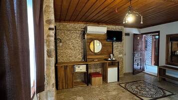 A room with a wooden ceiling, stone wall, and a bed.