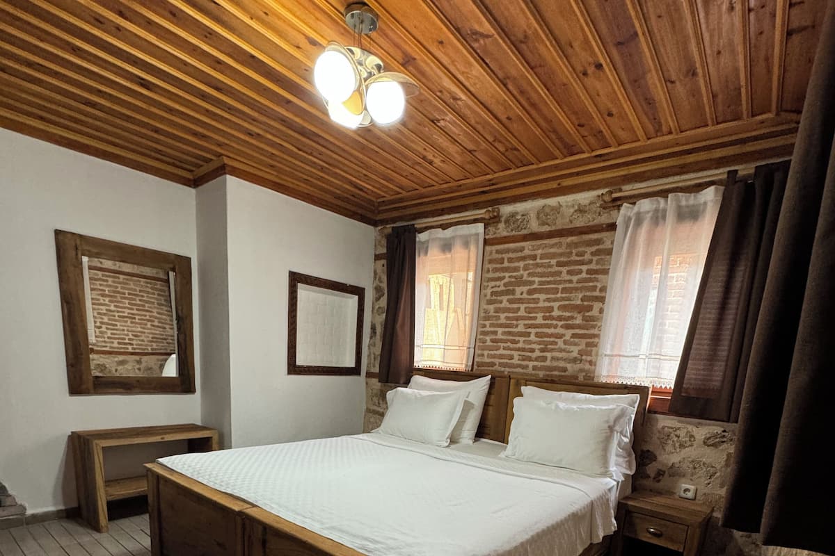 A wooden-paneled bedroom with a bed, a nightstand, a bench, and a ceiling fan.