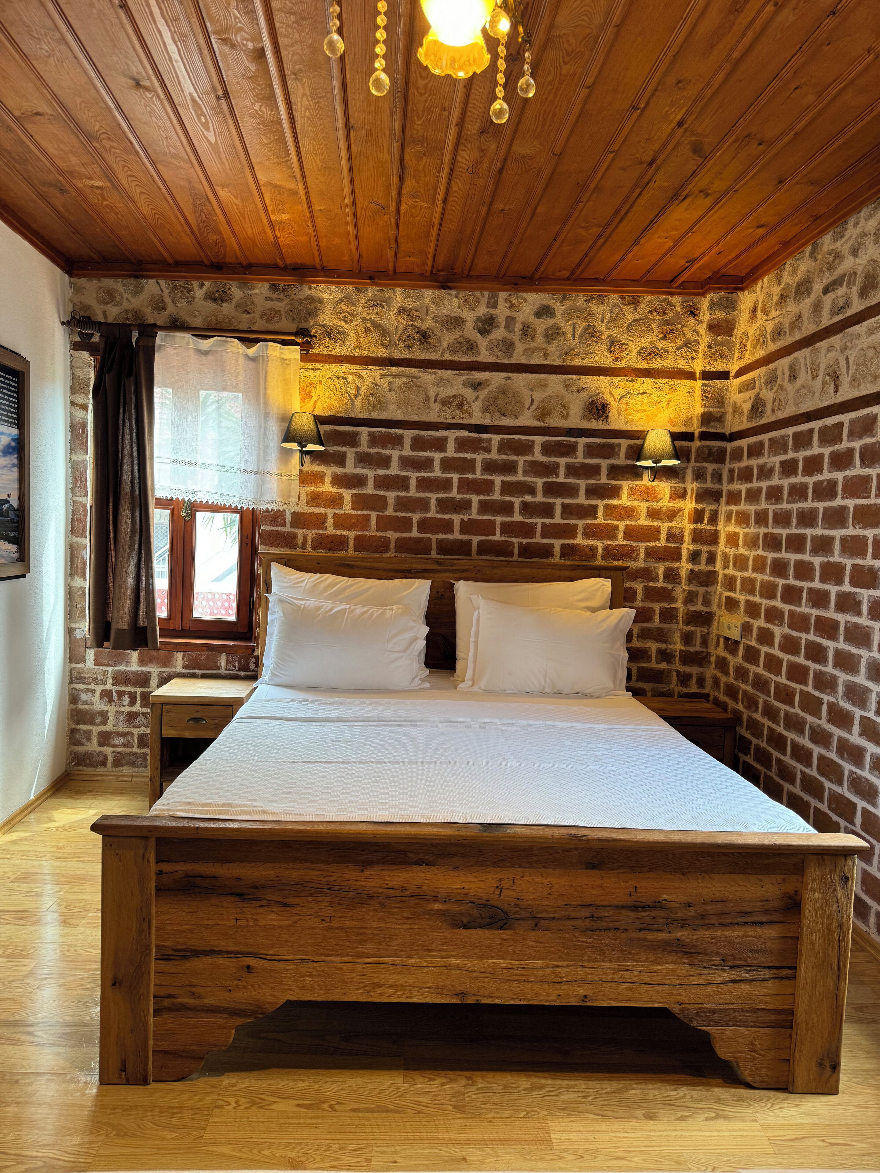 Una cama de madera en una habitación con paredes de ladrillo visto y techo de madera.