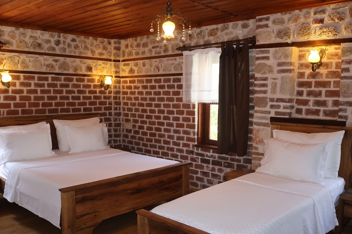 A room with two wooden beds, stone walls, and a wooden ceiling.