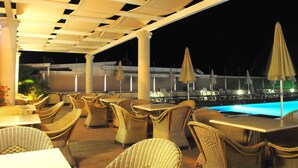 An outdoor patio area with wicker furniture and umbrellas, overlooking a pool. - Hotel Tokio Home-Tokio Beach dependence (Ravenna)