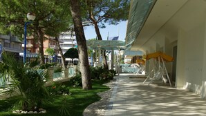 A pathway lined with trees and a building with a covered area. - Hotel Tokio Home-Tokio Beach dependence (Ravenna)