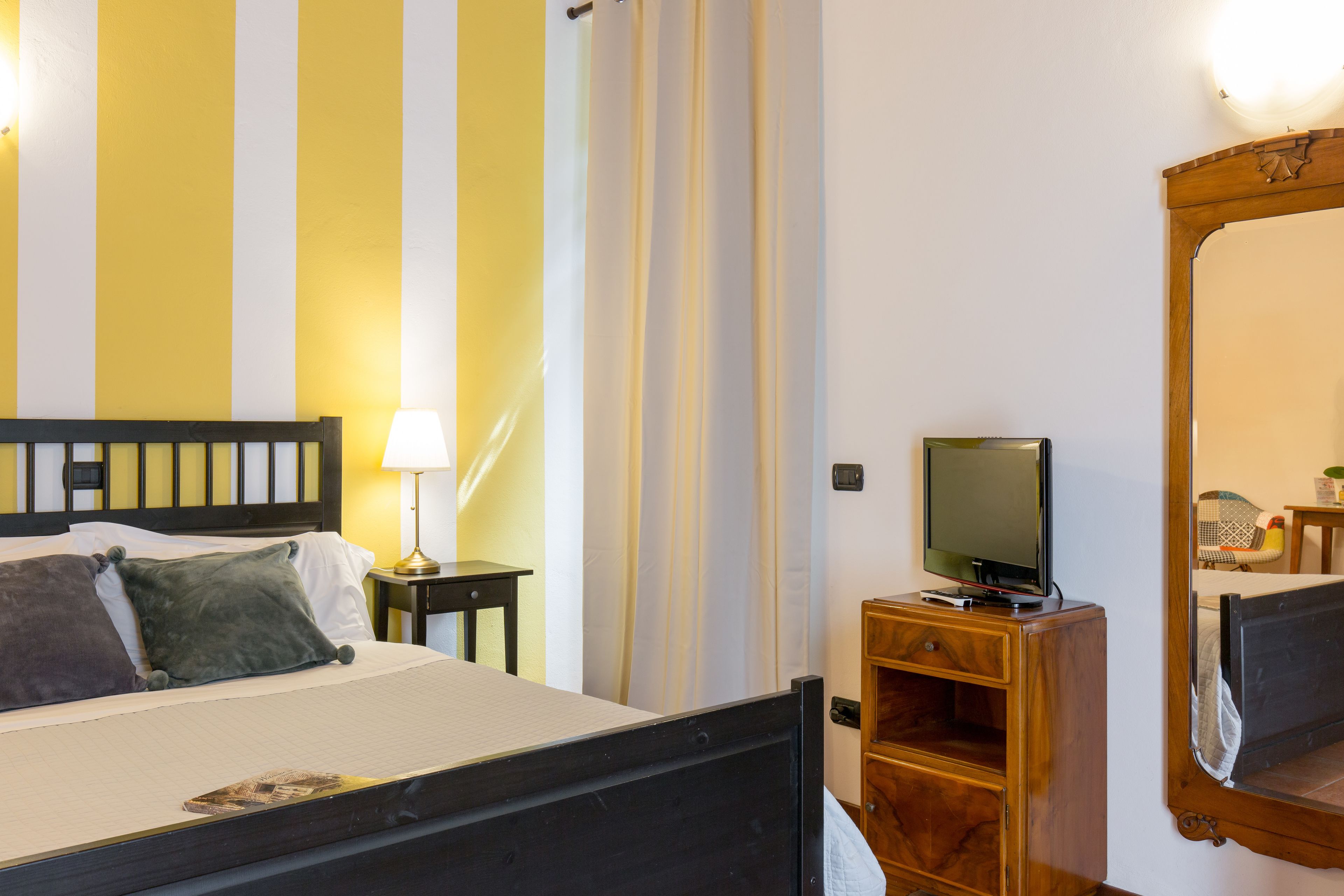 A hotel room with a bed, a TV, a lamp, and a wooden cabinet.