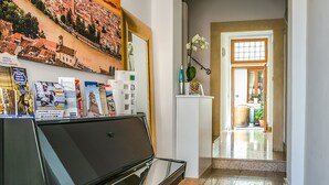 Un pasillo con un piano, un espejo, un cuadro enmarco y una puerta que da a otra habitación.