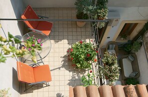 Une terrasse sur le toit, avec des chaises orange, une table et des plantes en pot.