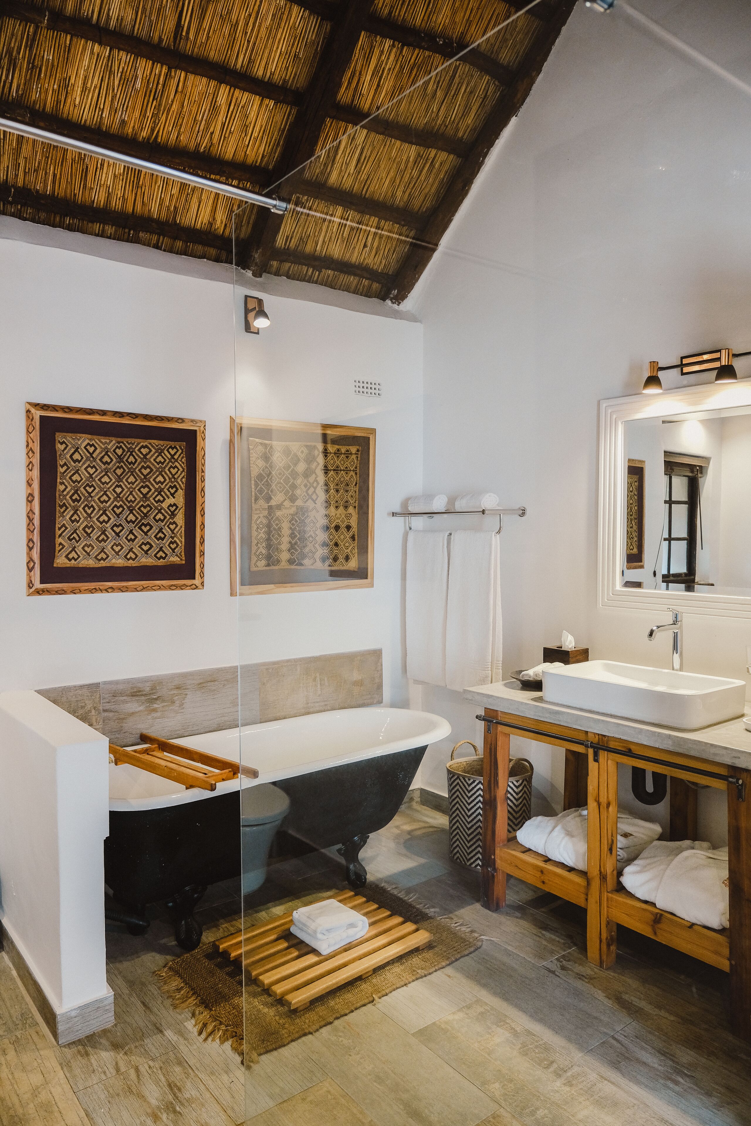 A modern bathroom with a bathtub, a wooden vanity, and a large mirror.