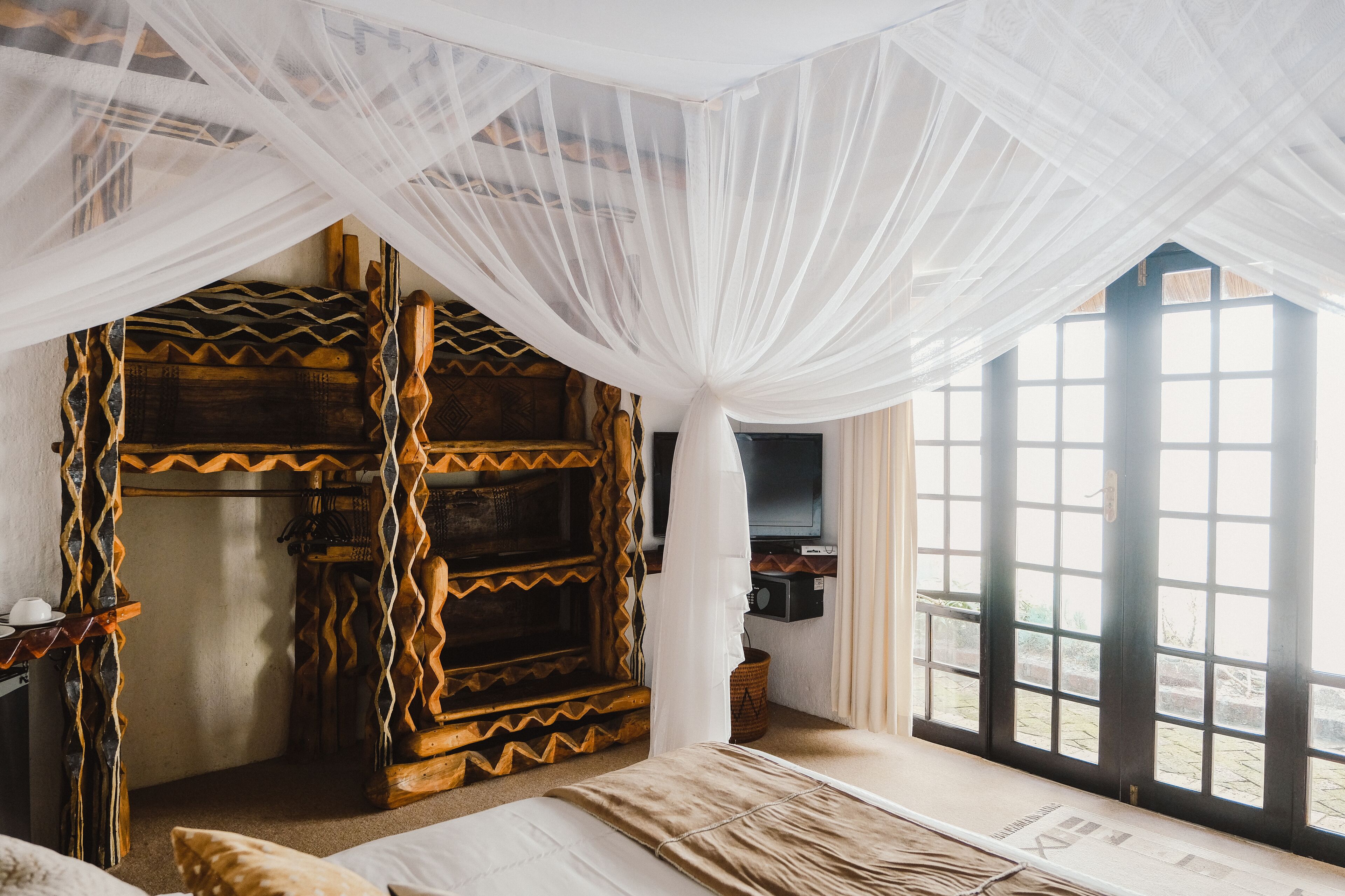 A room with a bed, a television, and a window with a view of the outside.