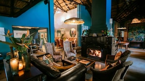 A cozy lounge area with leather sofas, a fireplace, and striped chairs.