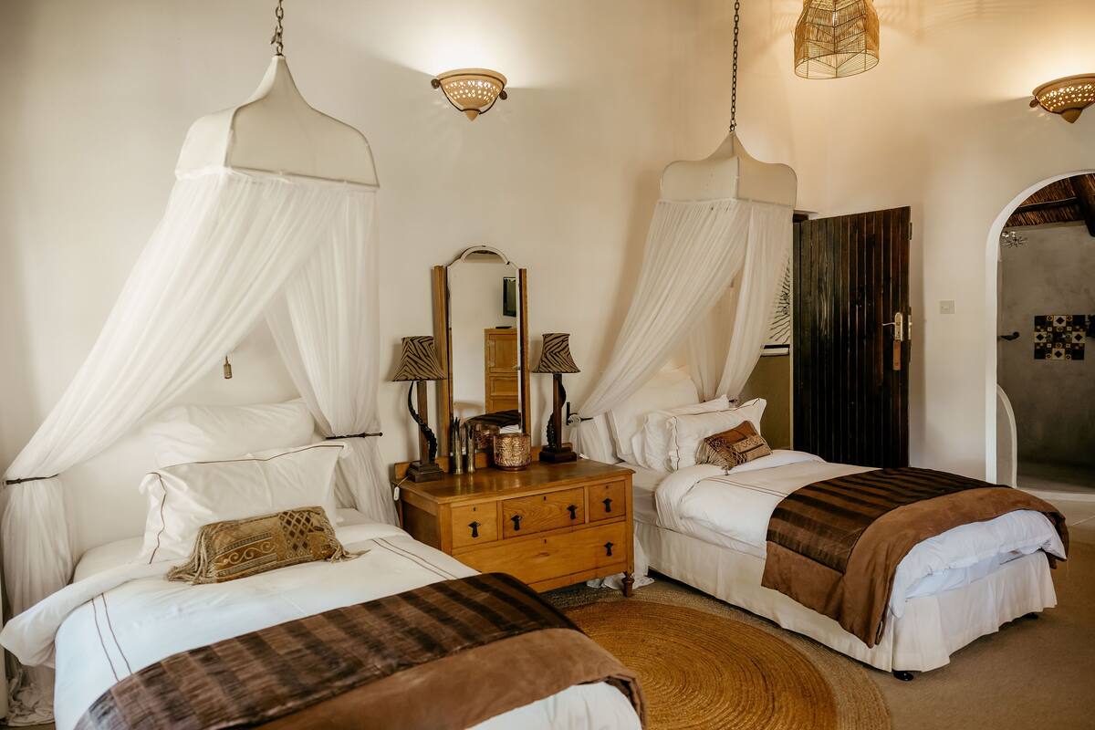 Quarto com duas camas, cômoda de madeira e espelho.