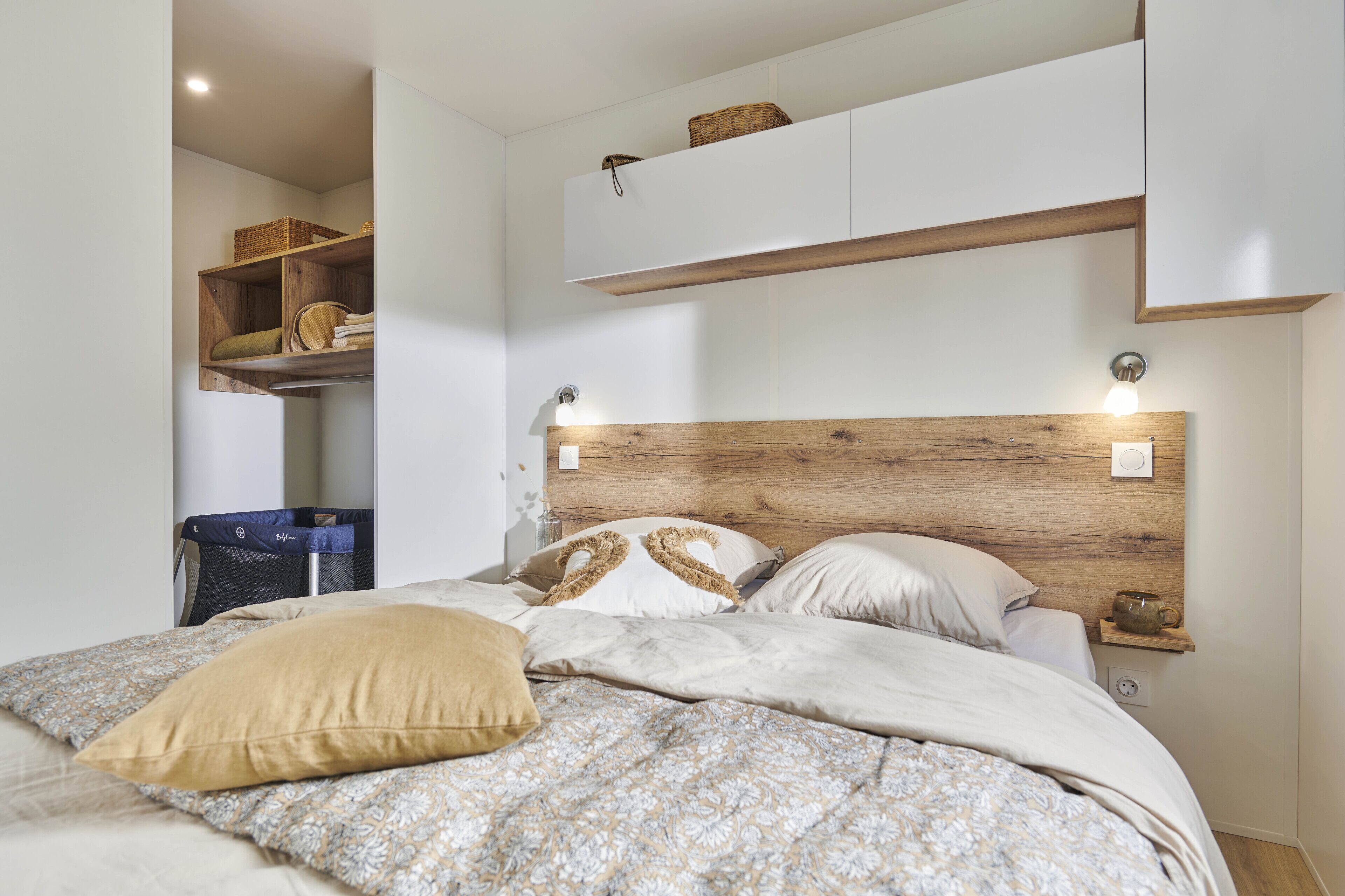 A bedroom with a bed, a nightstand, a wall-mounted shelf, and a wardrobe.
