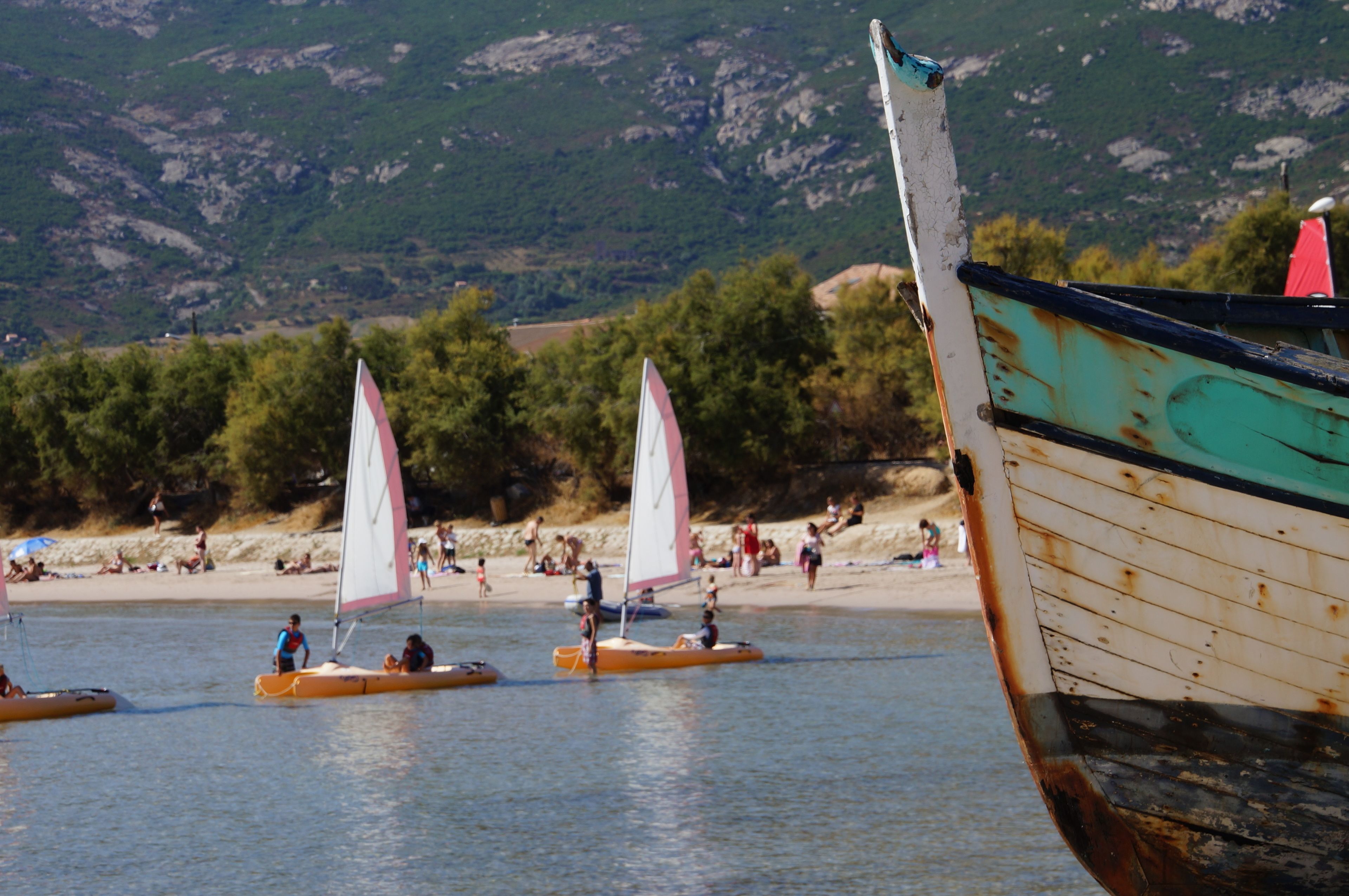 A beach with several boats and people.