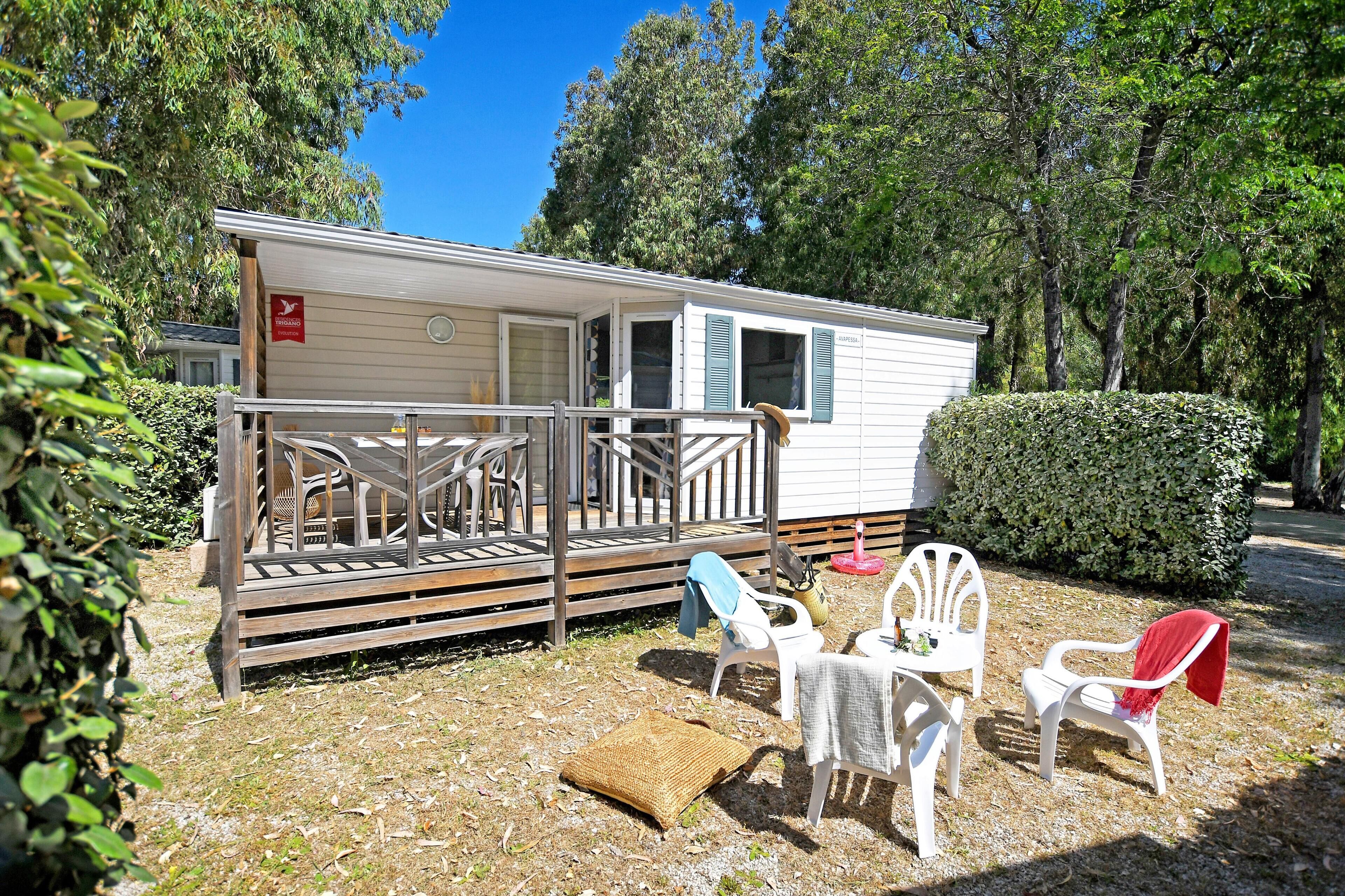 A mobile home with a porch, outdoor seating, and a small garden area.