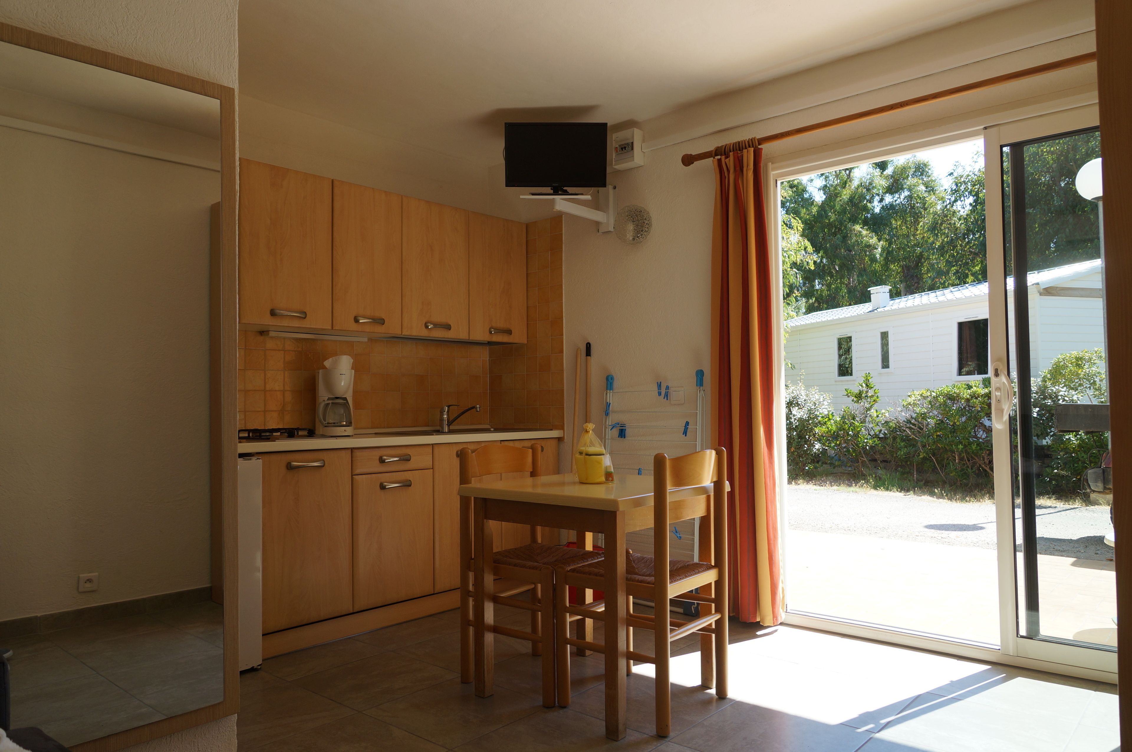 A kitchen with wooden cabinets, a coffee maker, and a table with chairs.