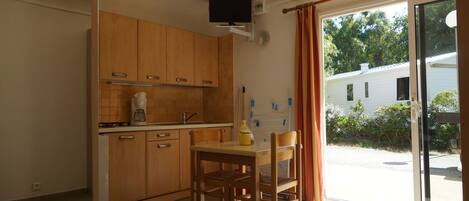 A kitchen with wooden cabinets, a coffee maker, and a table with chairs.
