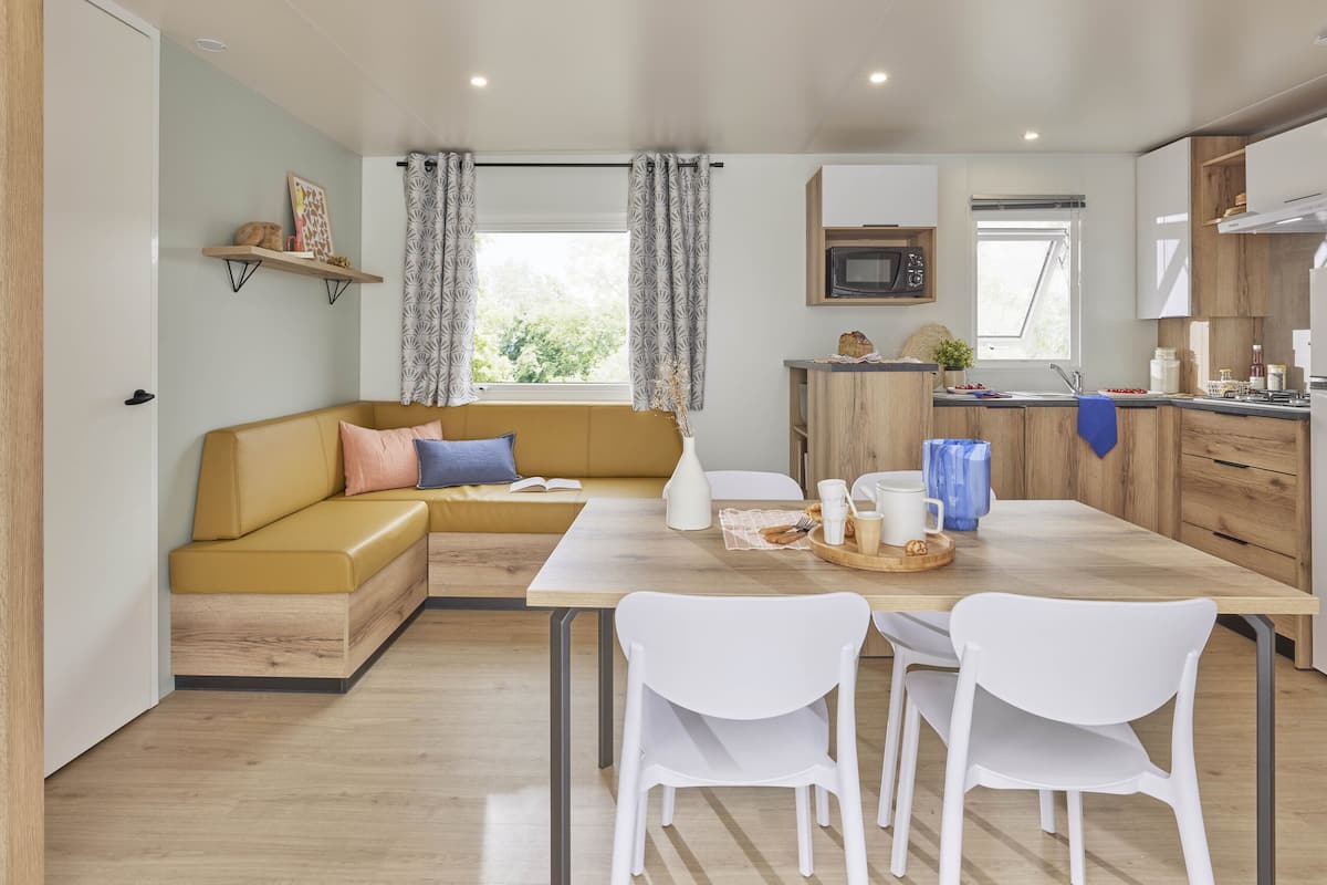 A modern kitchen with a wooden countertop, white chairs, and a built-in microwave.