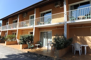 A multi-story building with balconies, outdoor seating, and potted plants. - Camping Les Castors (Calvi)