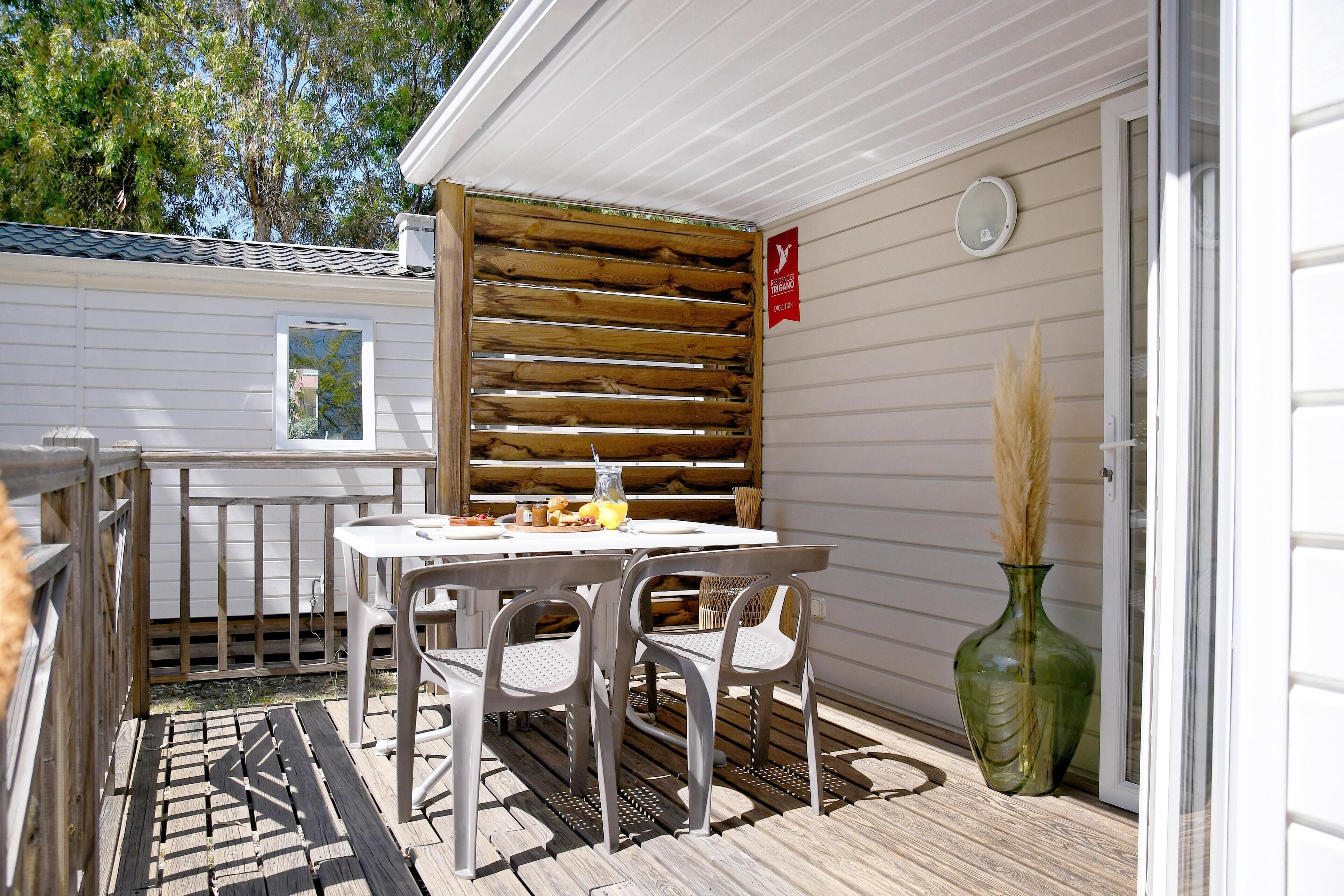 A patio with a table and chairs, a wooden fence, and a green vase.