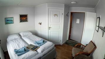 A bedroom with a bed, a chair, and two paintings on the wall.