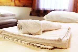 A neatly folded stack of white towels on a bed. - Mary-Ann's Polarrigg (Longyearbyen)