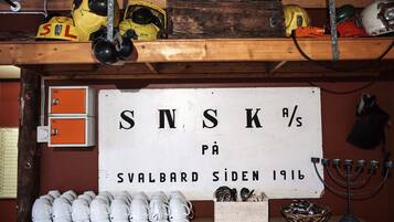 A room with a sign reading "SNSK %s på Svalbard Siden 1916" and a collection of white mugs on the floor.