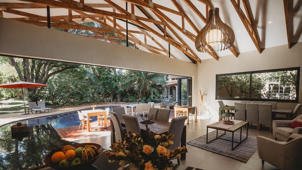 Una sala moderna con un ventanal grande, una piscina y mobiliario de exterior.