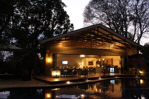 A modern building with a pool, wooden deck, and outdoor seating area. - Sandalwood Lodge (Harare)