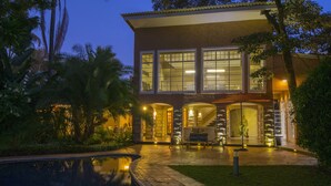 Una casa moderna con piscina, ventanas amplias y una entrada bien iluminada.