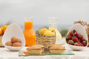 A breakfast setting with eggs, lemons, strawberries, and juice.