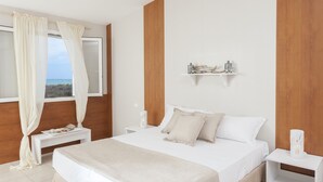 Un dormitorio con una cama grande, una mesita de noche, cortinas y vistas al mar.