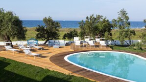 Zona de piscina con sillas de descanso y vista al mar.