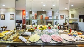 A buffet with various food items and a seating area with tables and chairs. - JR Hotel (Ribeirão Preto)