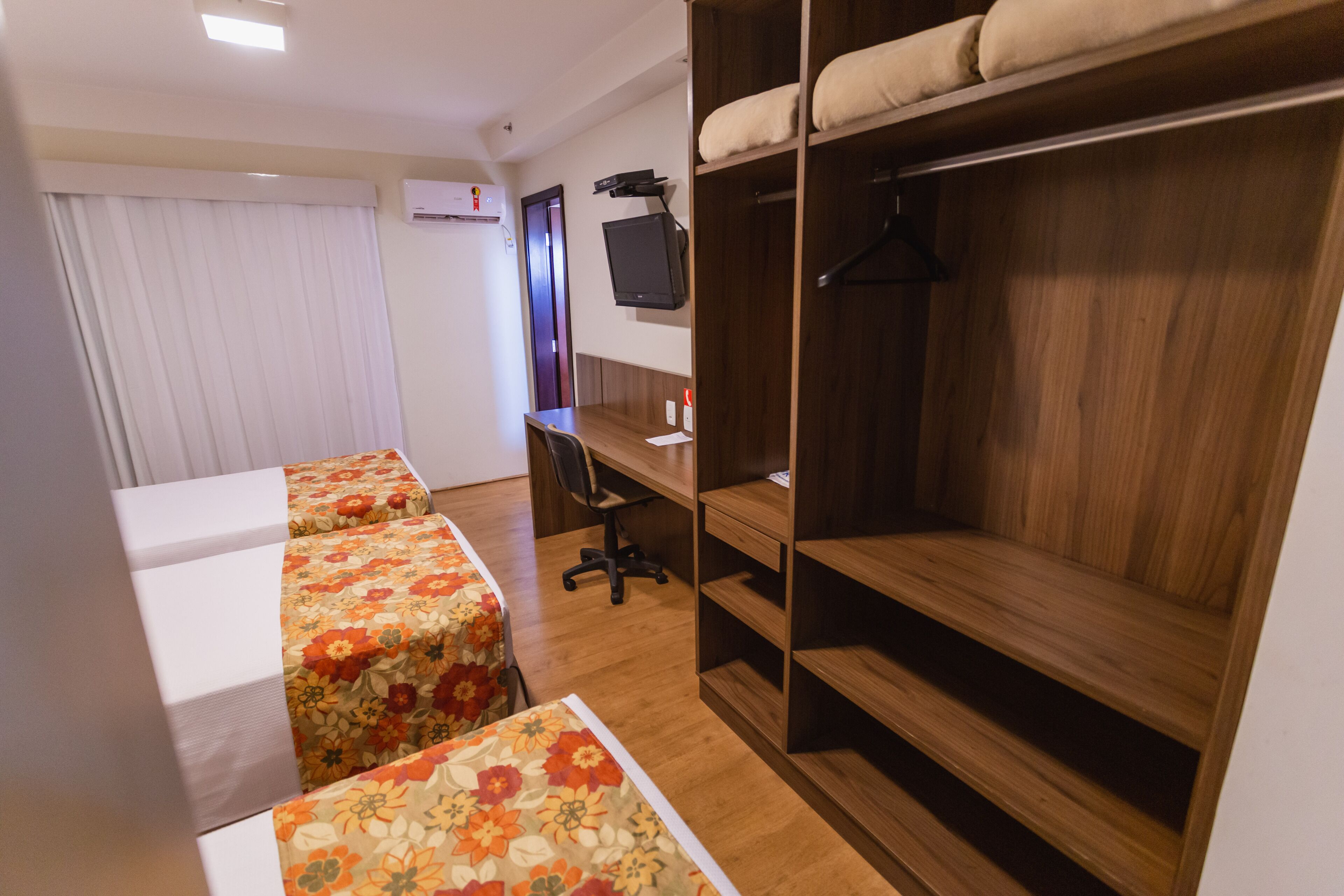 Una habitación de hotel con cama, escritorio y armario.