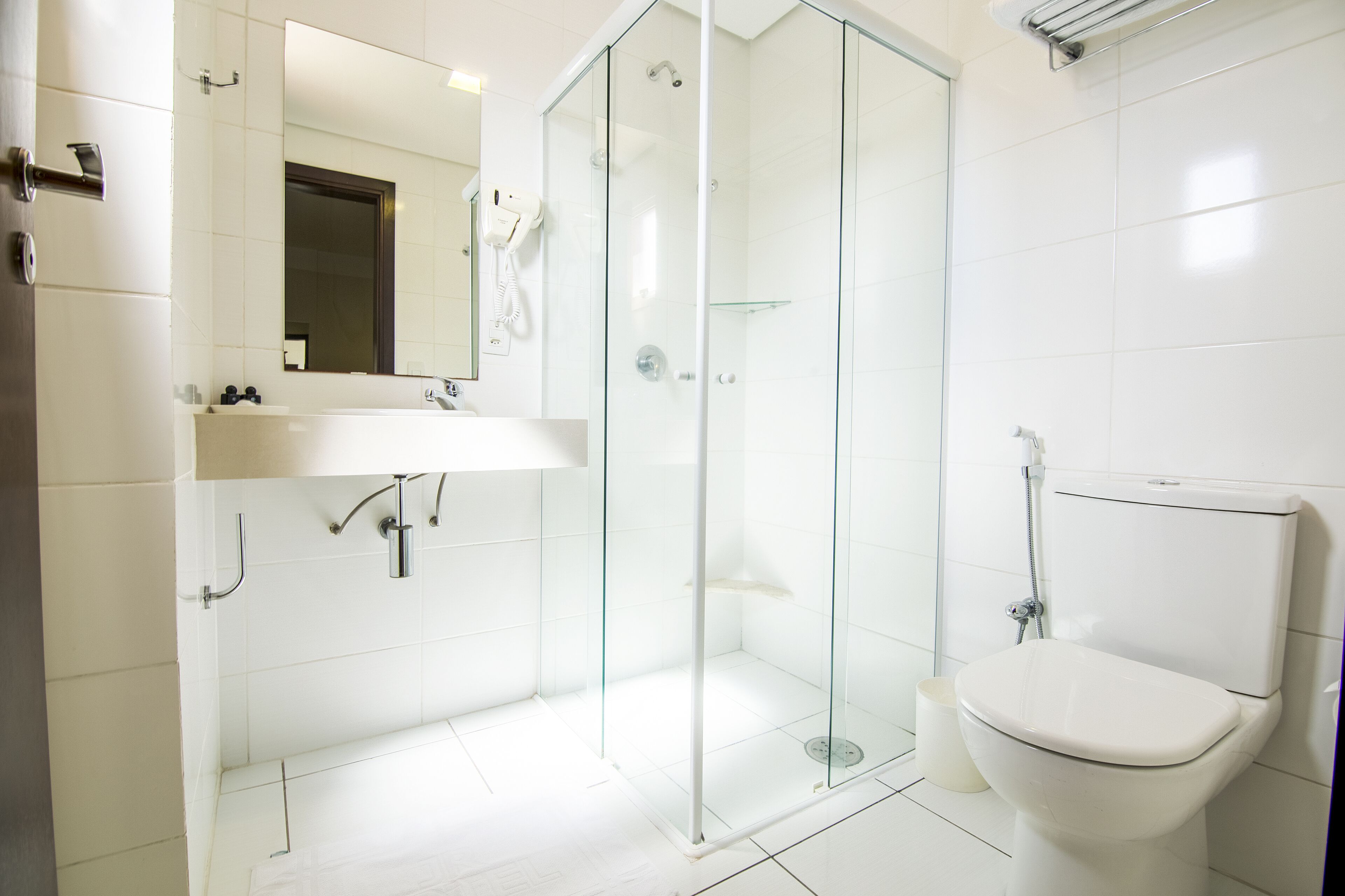A modern bathroom with a glass-enclosed shower, a white sink, and a toilet.