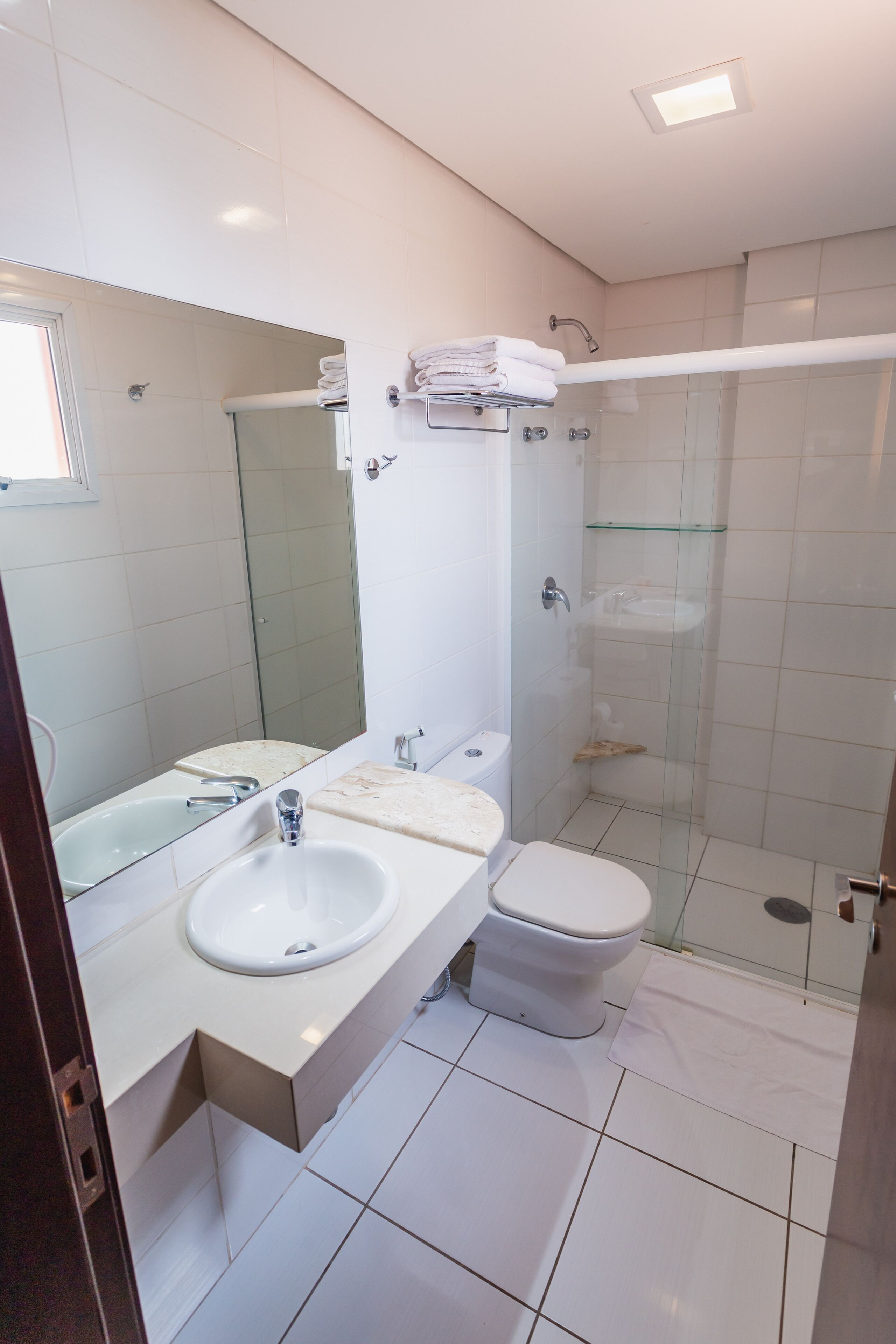 A modern bathroom with a white sink, toilet, and glass shower enclosure.