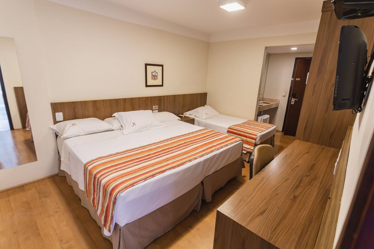Una camera d'albergo con due letti, una scrivania in legno e un tavolino.