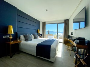 A hotel room with a large bed, a desk, and a view of the sea. - Hotel Art Santander (Santander)