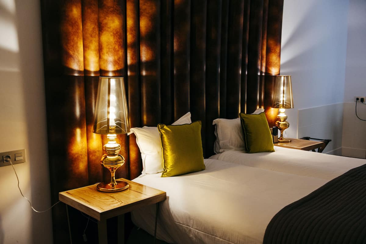 A hotel room with a large bed, two bedside tables with lamps, and a curtain backdrop.