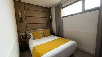 A hotel room with a bed, a nightstand, a lamp, and a window with curtains.