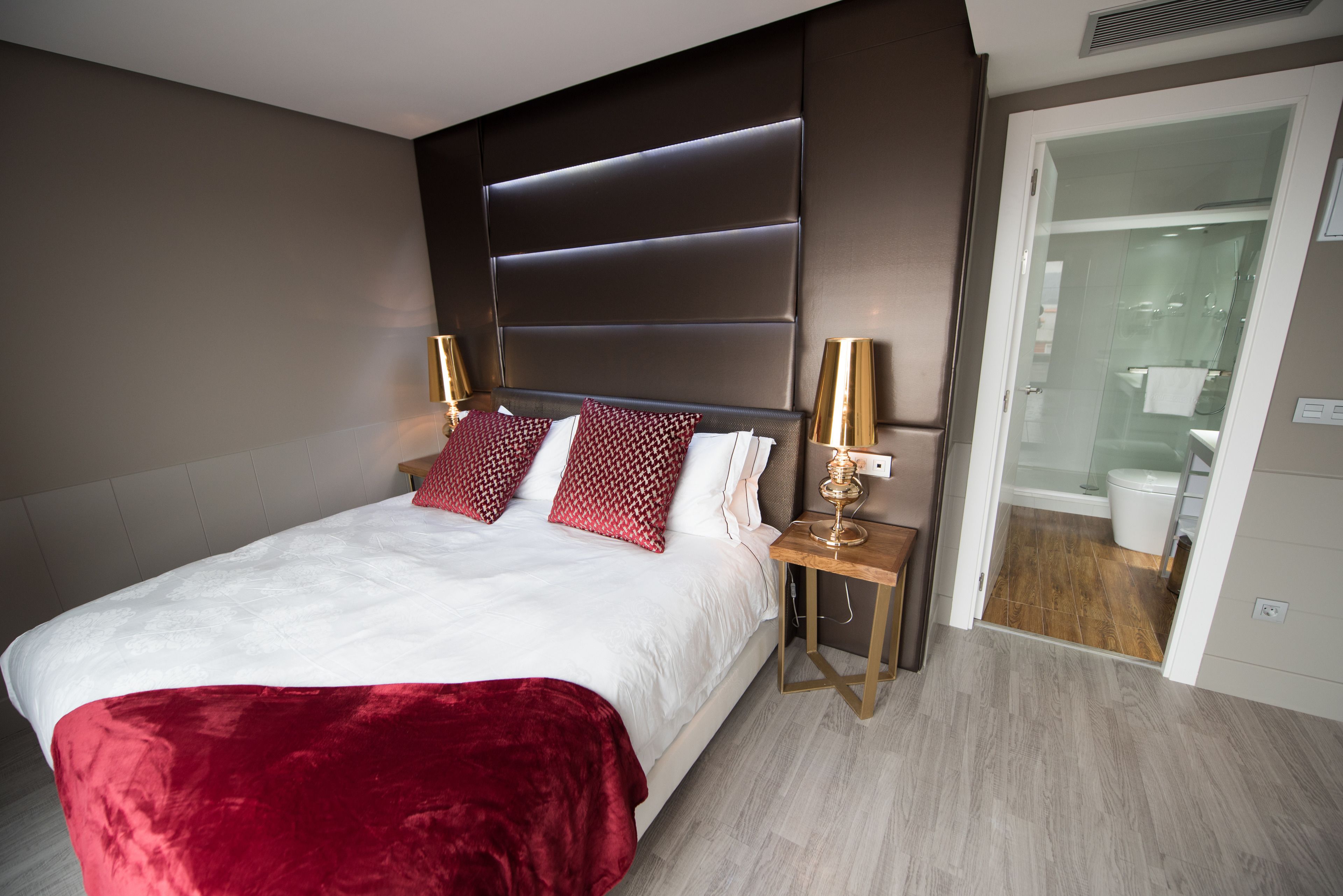 A modern hotel room with a large bed, a bedside table with a lamp, and a view of the bathroom.