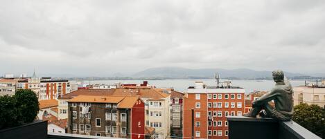 A rooftop terrace with a view of a cityscape and a body of water.