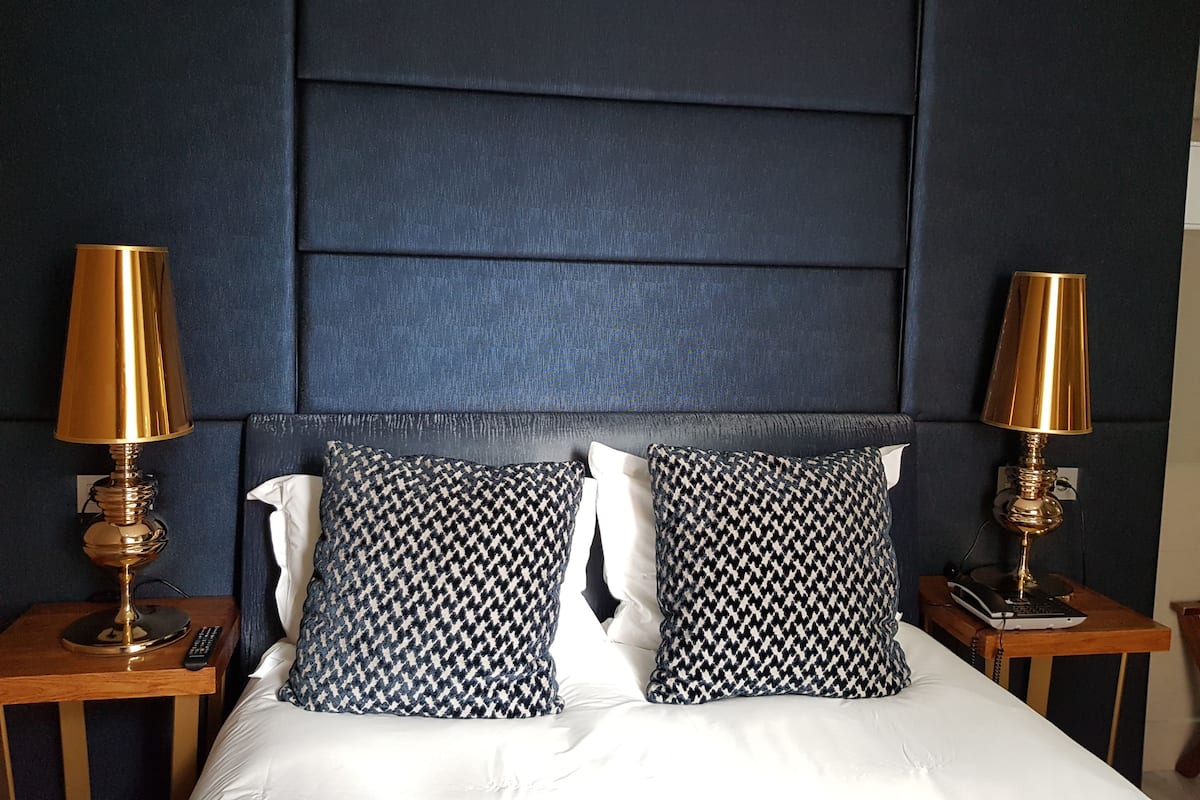 A hotel room with a large bed, two bedside tables, two lamps, and a headboard.