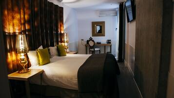 Habitación de hotel con una cama grande, lámparas de noche, un escritorio con espejo y un televisor fijado a la pared.