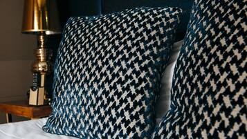 A bed with two houndstooth patterned pillows and a gold-colored lamp beside it.