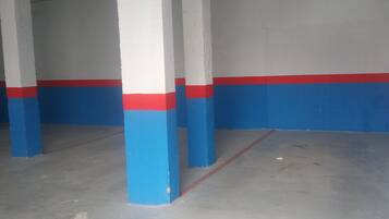Un garaje para estacionar con columnas pintadas en azul y rojo, y un piso de concreto.