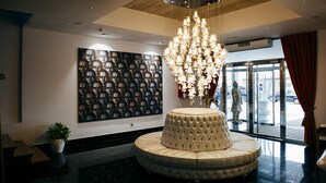 Um hall de entrada com um grande candelabro, uma área de estar circular e uma parede com um padrão de capacetes.