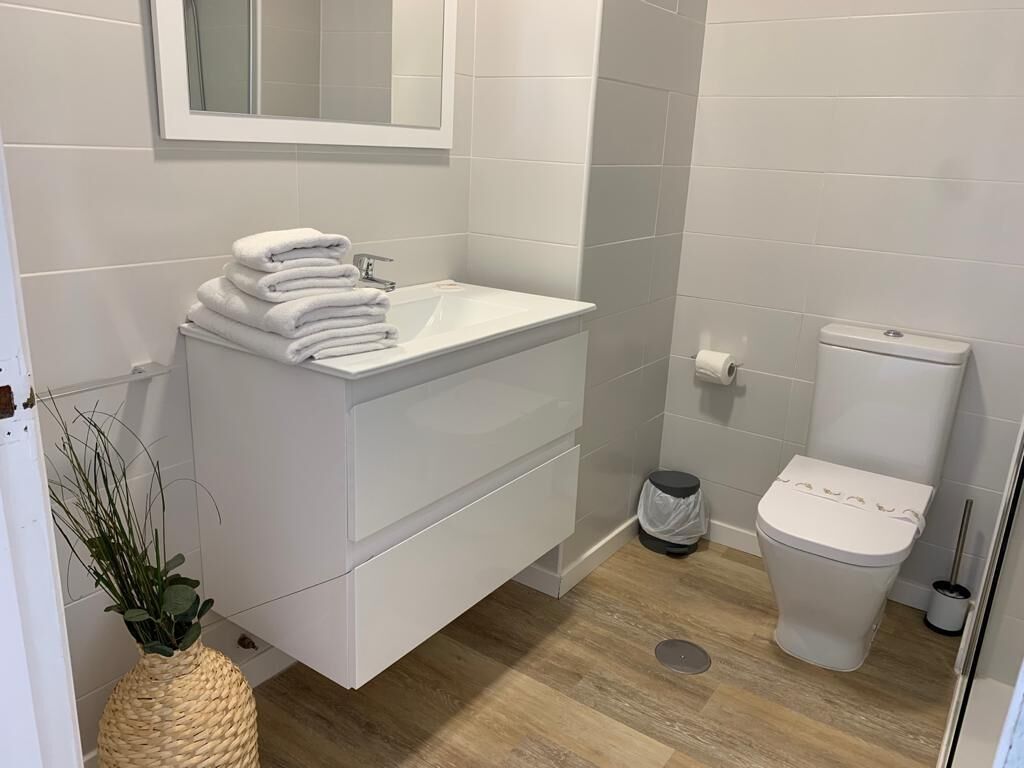 Ein Badezimmer mit weißem Waschtisch, Toilette und Spiegel über dem Waschbecken.