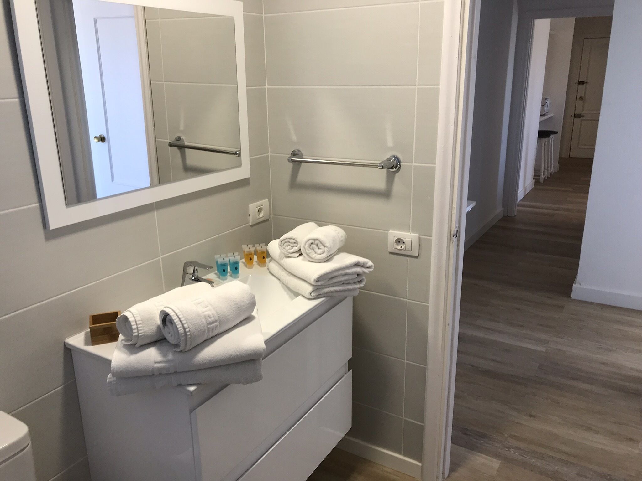 Un bagno moderno con un mobile lavabo bianco, un portascopevoli e uno specchio.