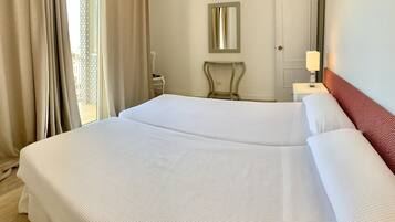 A hotel room with a large bed, a bedside table with a lamp, a chair, and a mirror on the wall.