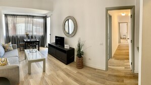 Ein modernes Wohnzimmer mit einer Couch, einem Couchtisch, einem Fernseher und einem Essbereich mit Tisch und Stühlen.
